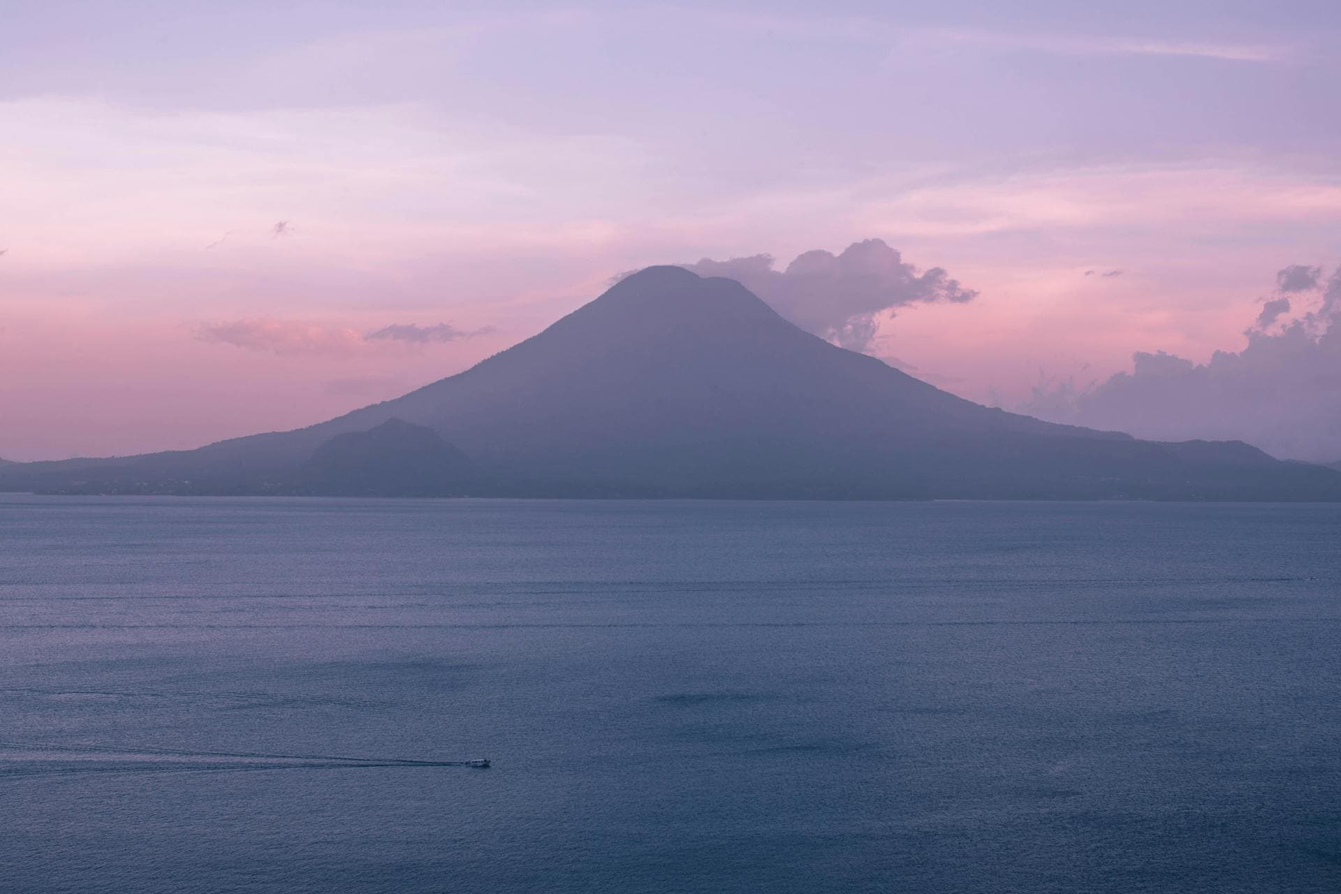 Lake Atitlan at sunset framed by volcanic peaks in Guatemala