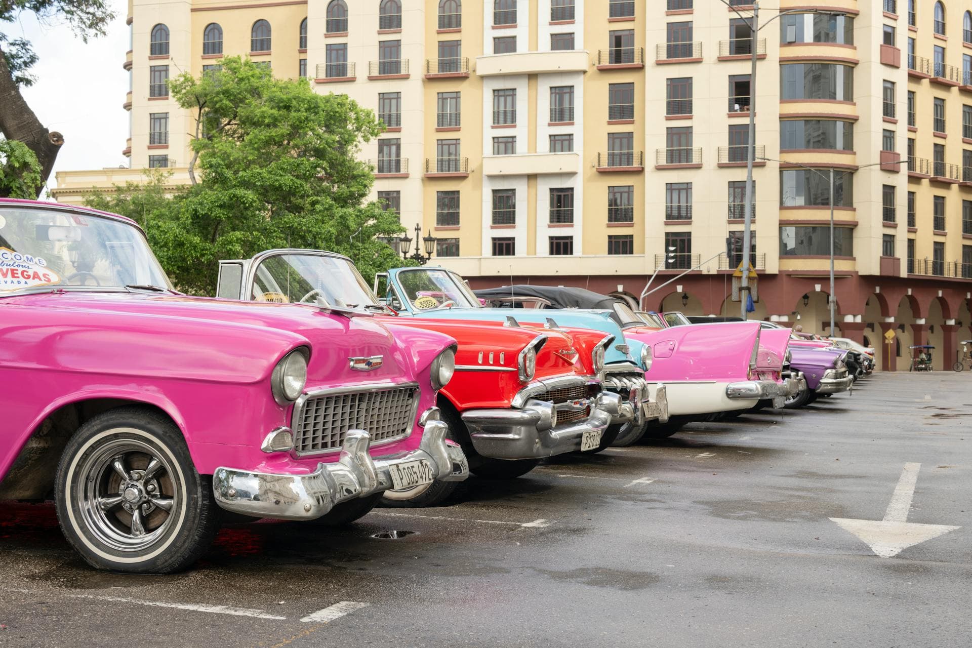 Colourful vintage American cars lined up on a street in Havana, Cuba, with classic colonial architecture behind