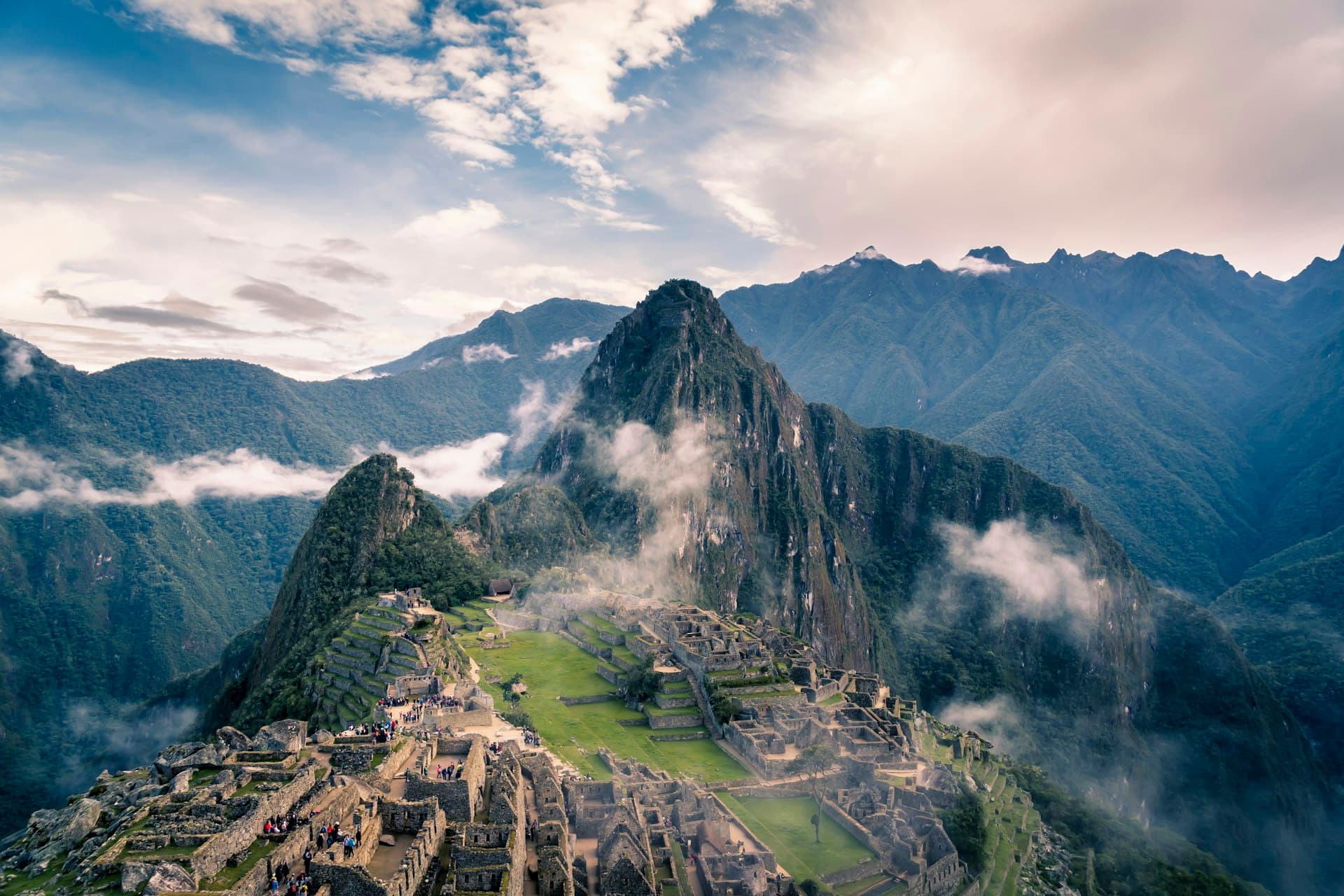 Hikers approaching the ancient Inca ruins of Machu Picchu along a mountain trail in Peru