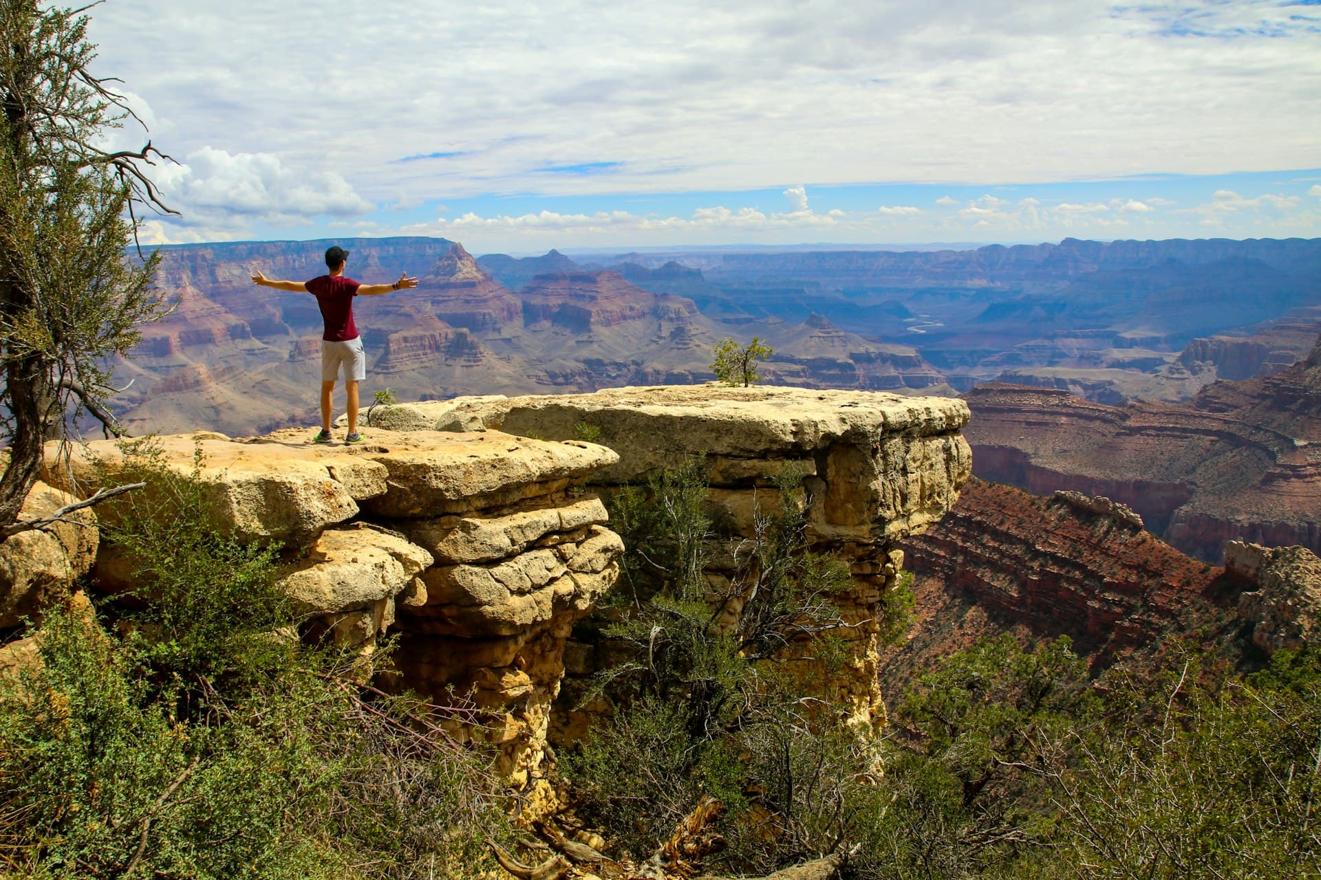 Hiker with outstretched arms overlooking the vast Grand Canyon at golden hour, Arizona, USA