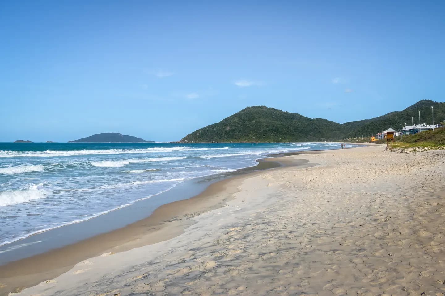 A wide sandy beach with rolling surf and green hills at Florianopolis, southern Brazil