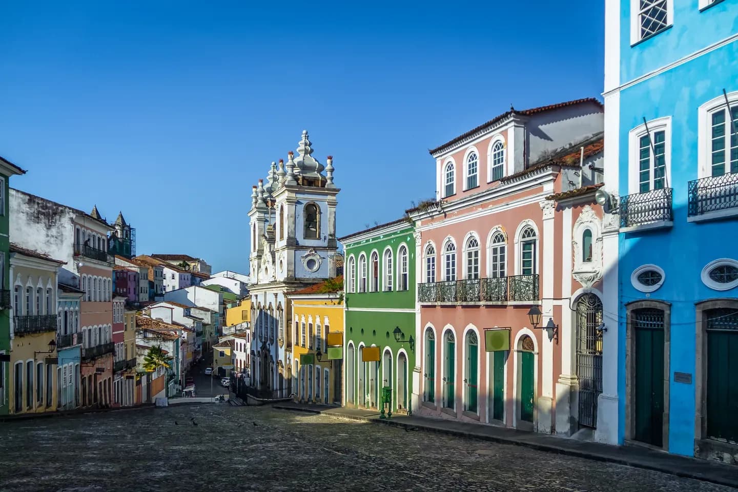 Colourful colonial houses and a church tower on a cobbled street in the Pelourinho district of Salvador, Bahia