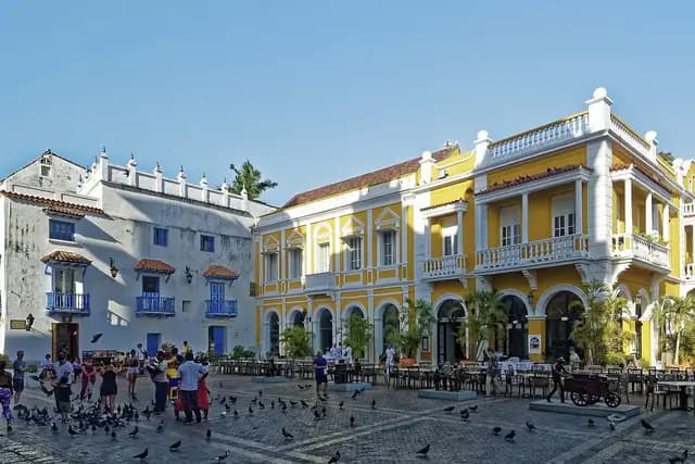 Colonial plaza with yellow buildings and people in the walled city of Cartagena, Colombia