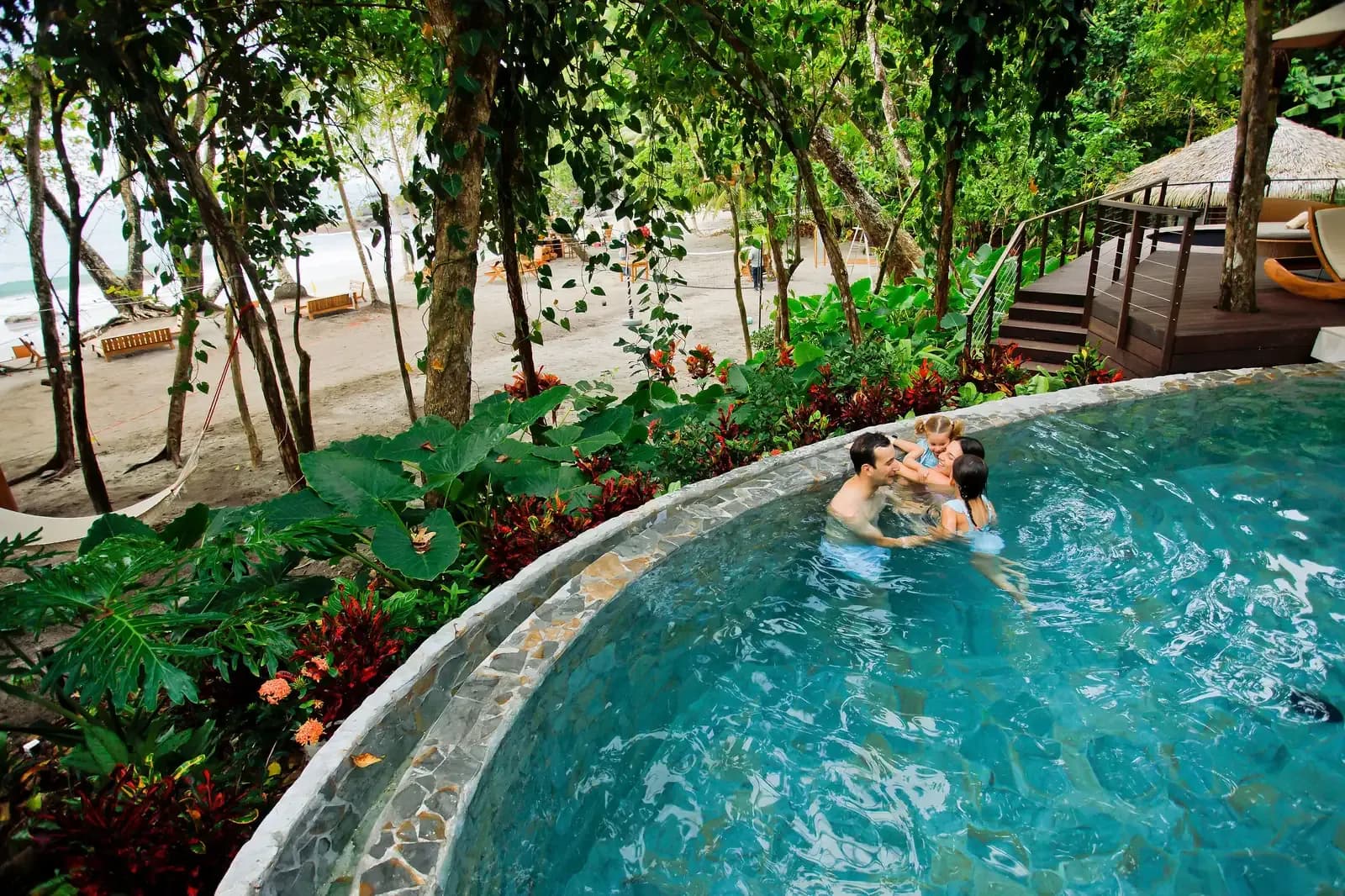 A couple in the pool above the beach at Arenas del Mar, Manuel Antonio, rainforest all around