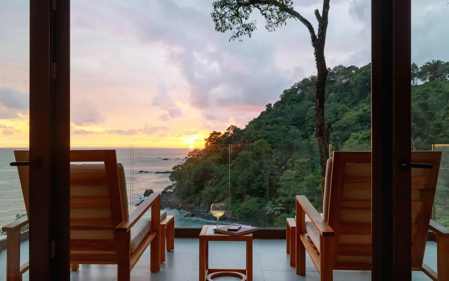 Sunset over the Pacific from the terrace of an Ocean View Premium Suite at Arenas del Mar, Manuel Antonio, two chairs and a glass of wine