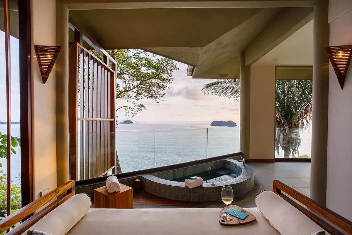 Private terrace of an Ocean View Premium Suite at Arenas del Mar with a hot tub, two glasses of wine and the Pacific beyond