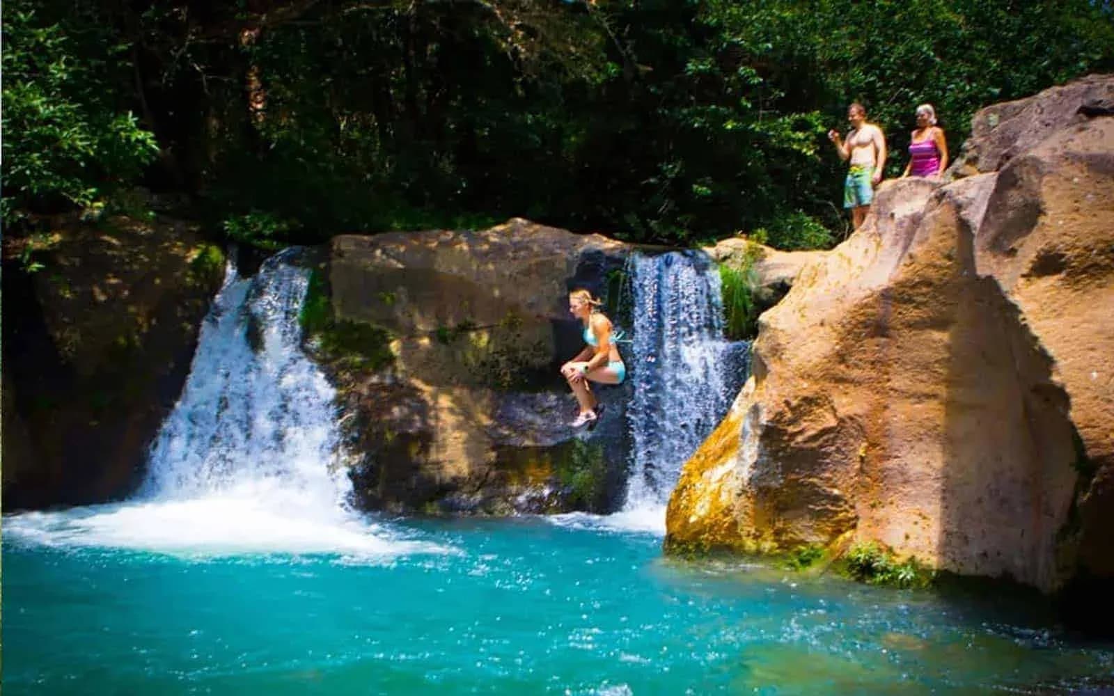 Traveller leaping into a turquoise waterfall pool near Rincón de la Vieja, Costa Rica