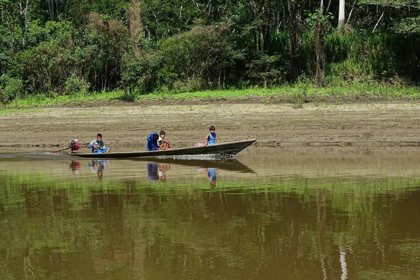 A motor canoe on the calm Arajuno river with rainforest on the far bank, Napo, Ecuador