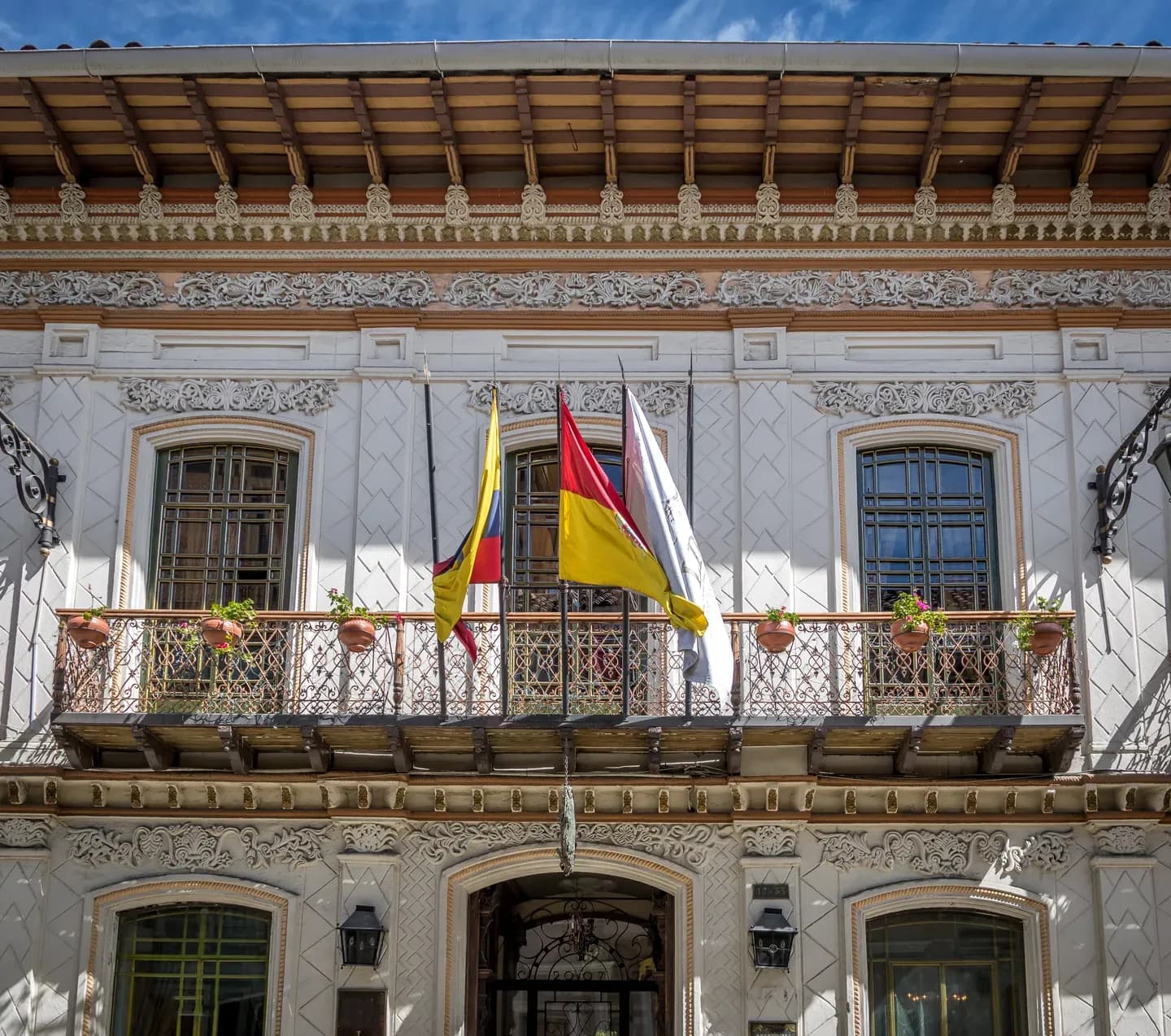 A carved colonial facade with a flag-hung balcony in the old centre of Cuenca, Ecuador