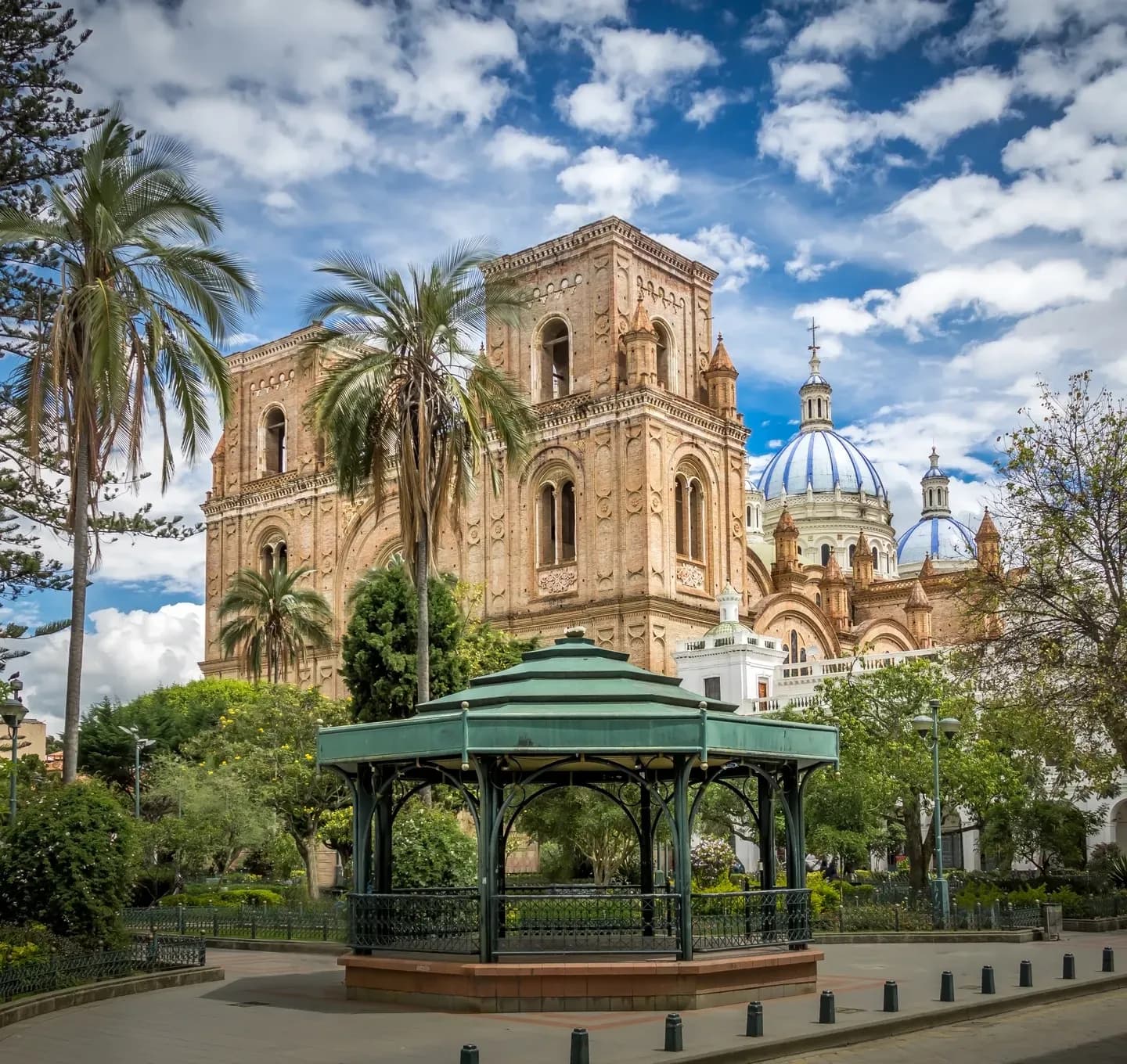 The brick New Cathedral with its blue domes behind the bandstand and palms of Parque Calderon, Cuenca, Ecuador