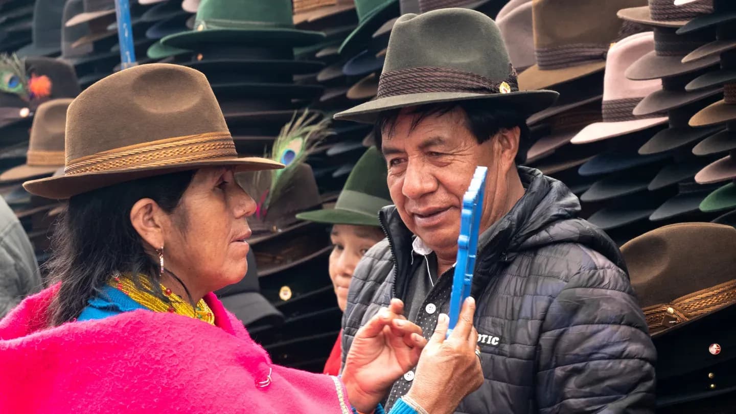 Two people choosing a felt hat at a market stall in Ecuador
