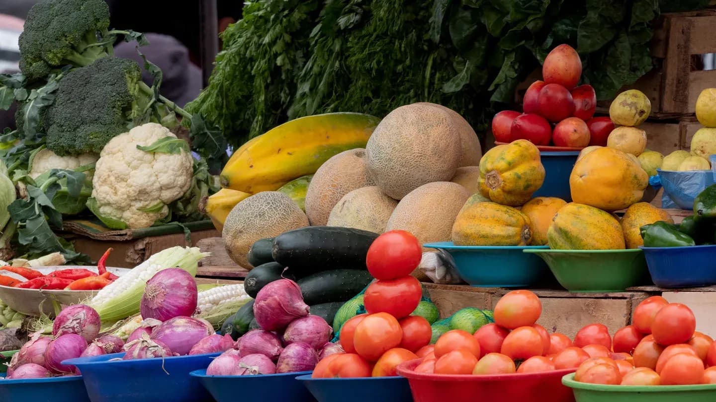 Melons, tomatoes, papayas and onions piled on a market stall in Ecuador