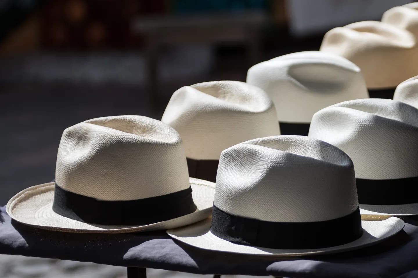Rows of white Panama hats with black bands in the sun at a market in Otavalo, Ecuador