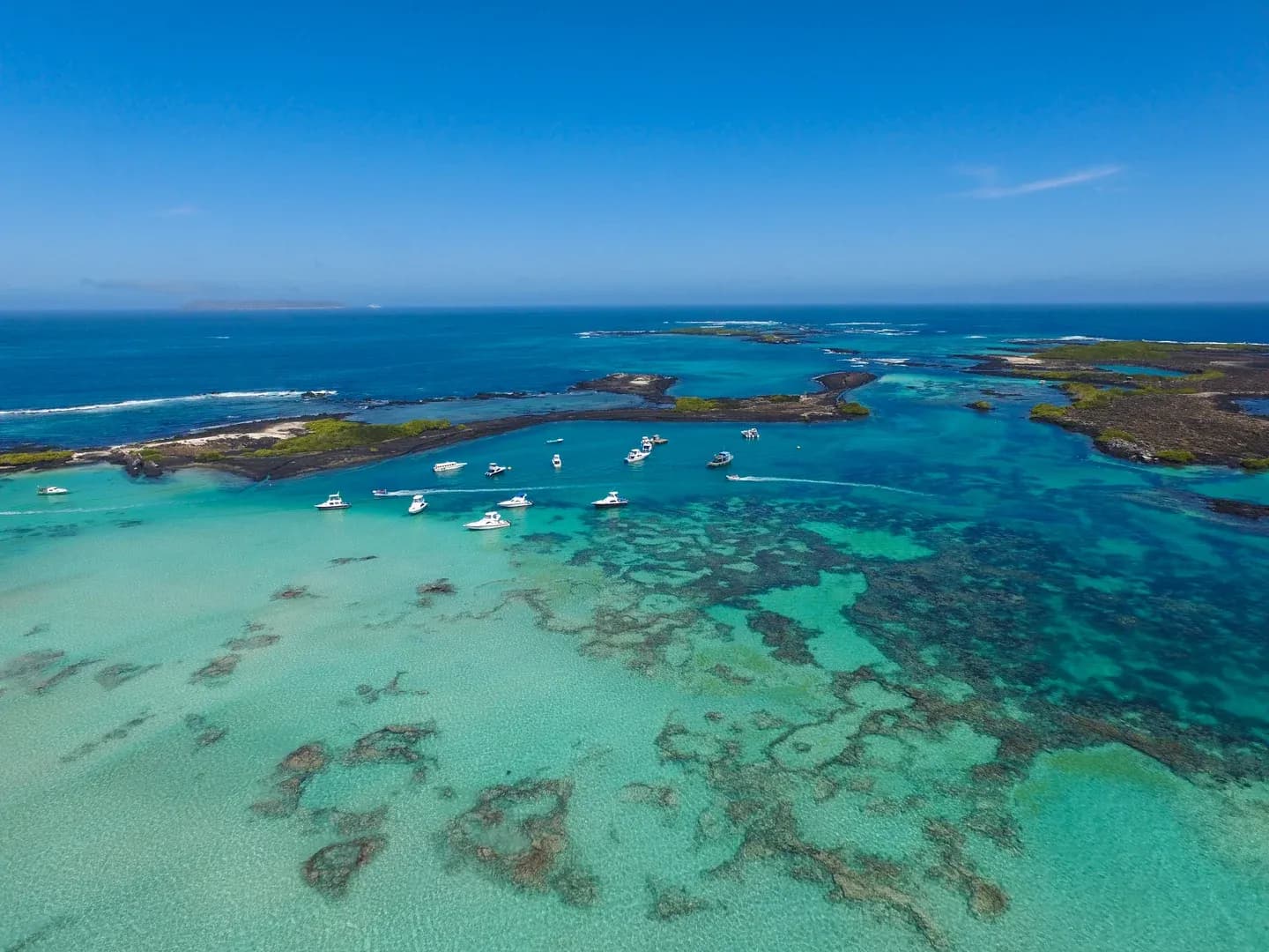 Turquoise shallows and anchored boats off Isabela Island in the Galápagos, from the air