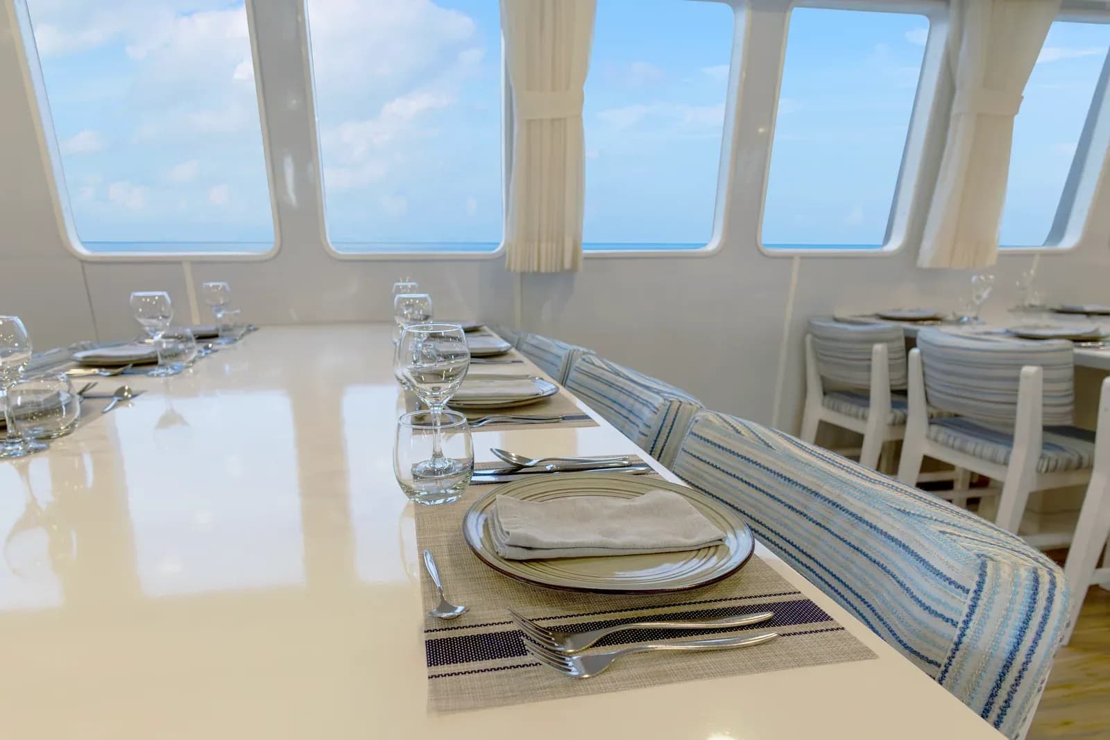 Table set for dining with ocean-view windows aboard Galaxy Diver II, Galápagos