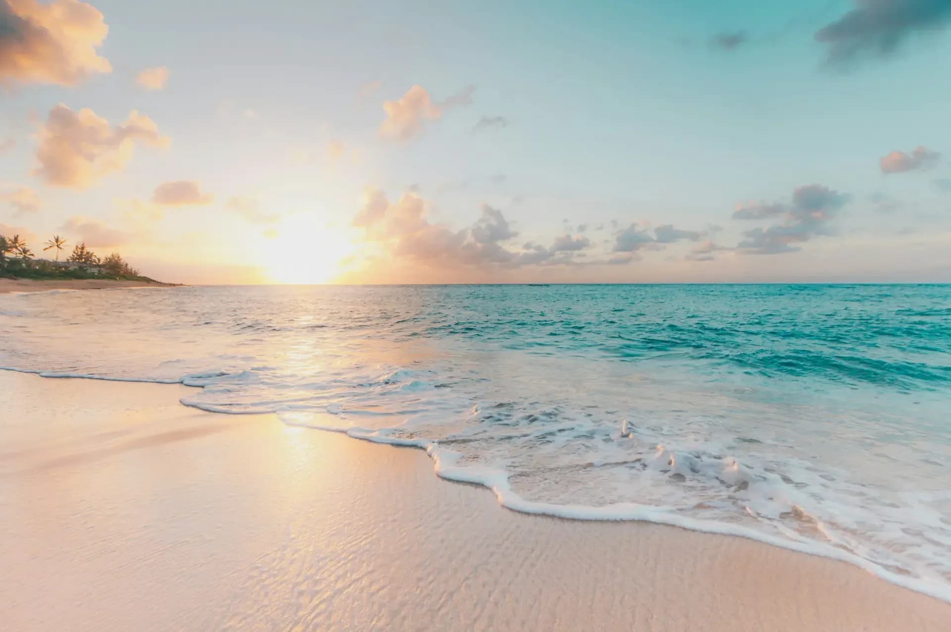 Turquoise ocean waves rolling onto a white sandy tropical beach under clear skies