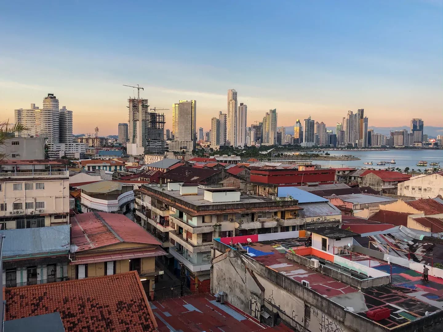 Old red-tiled rooftops of Panama City with the modern skyline behind at sunset