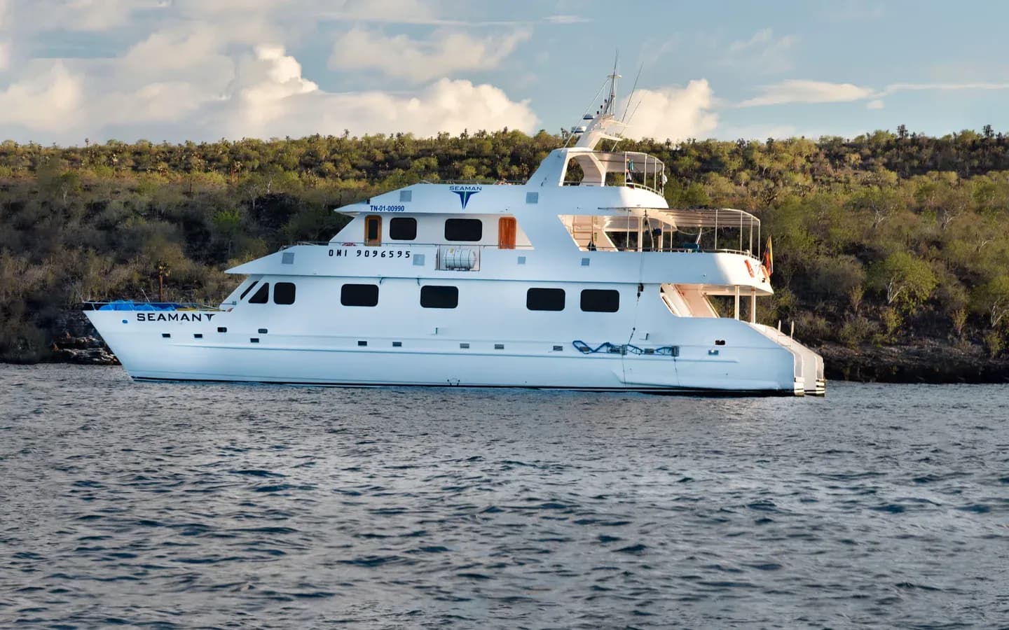 Seaman Journey catamaran anchored off a volcanic coastline, Galápagos