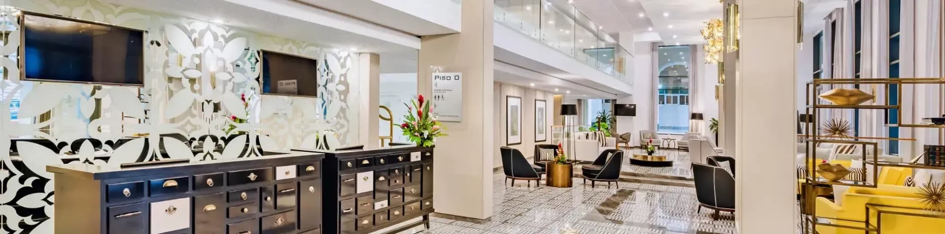 A modern hotel lobby with a stylish reception desk, seating areas, and a multi-level interior.