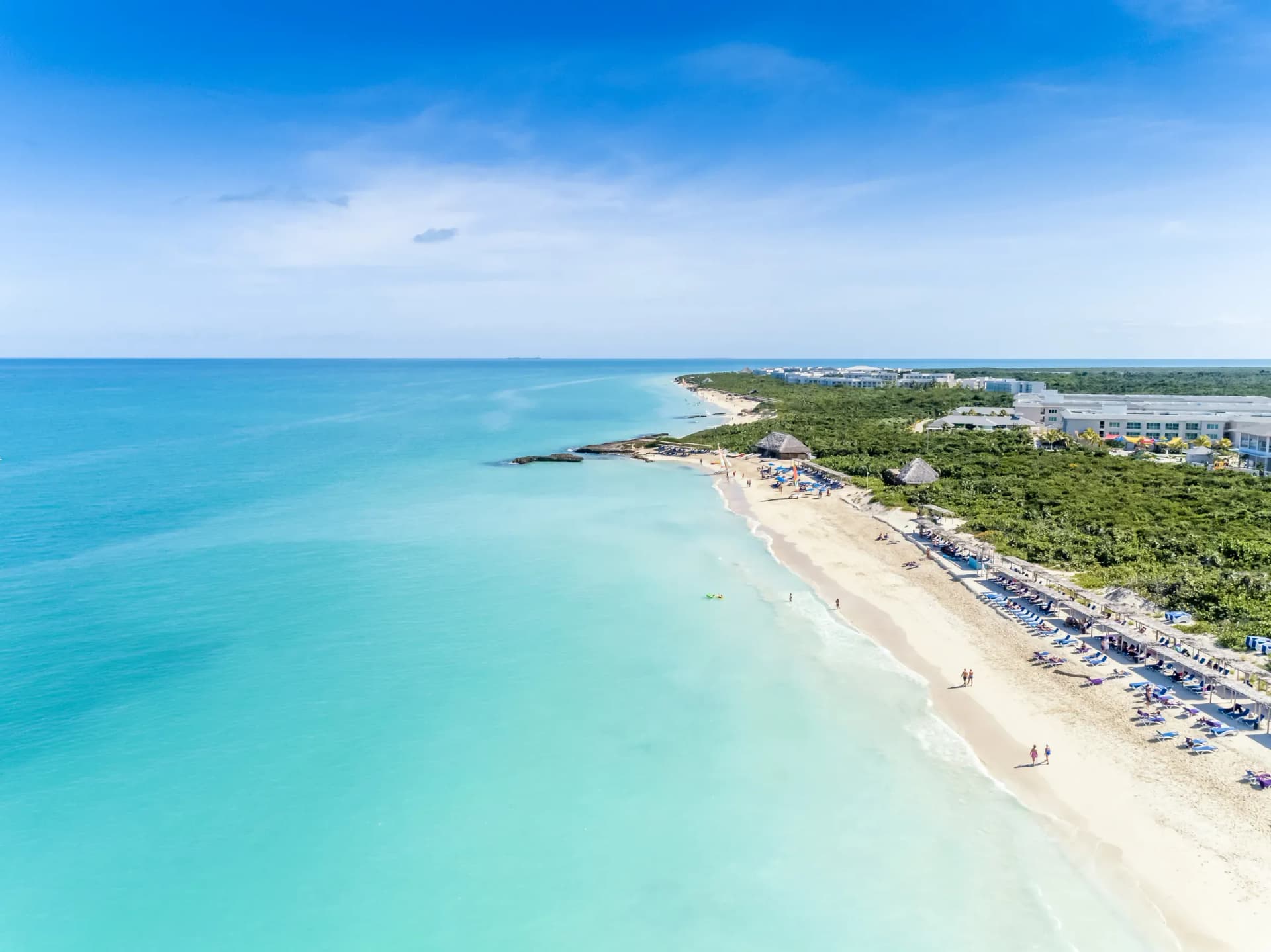 Long white-sand beach with sunbeds and clear turquoise water at Cayo Santa María, Cuba