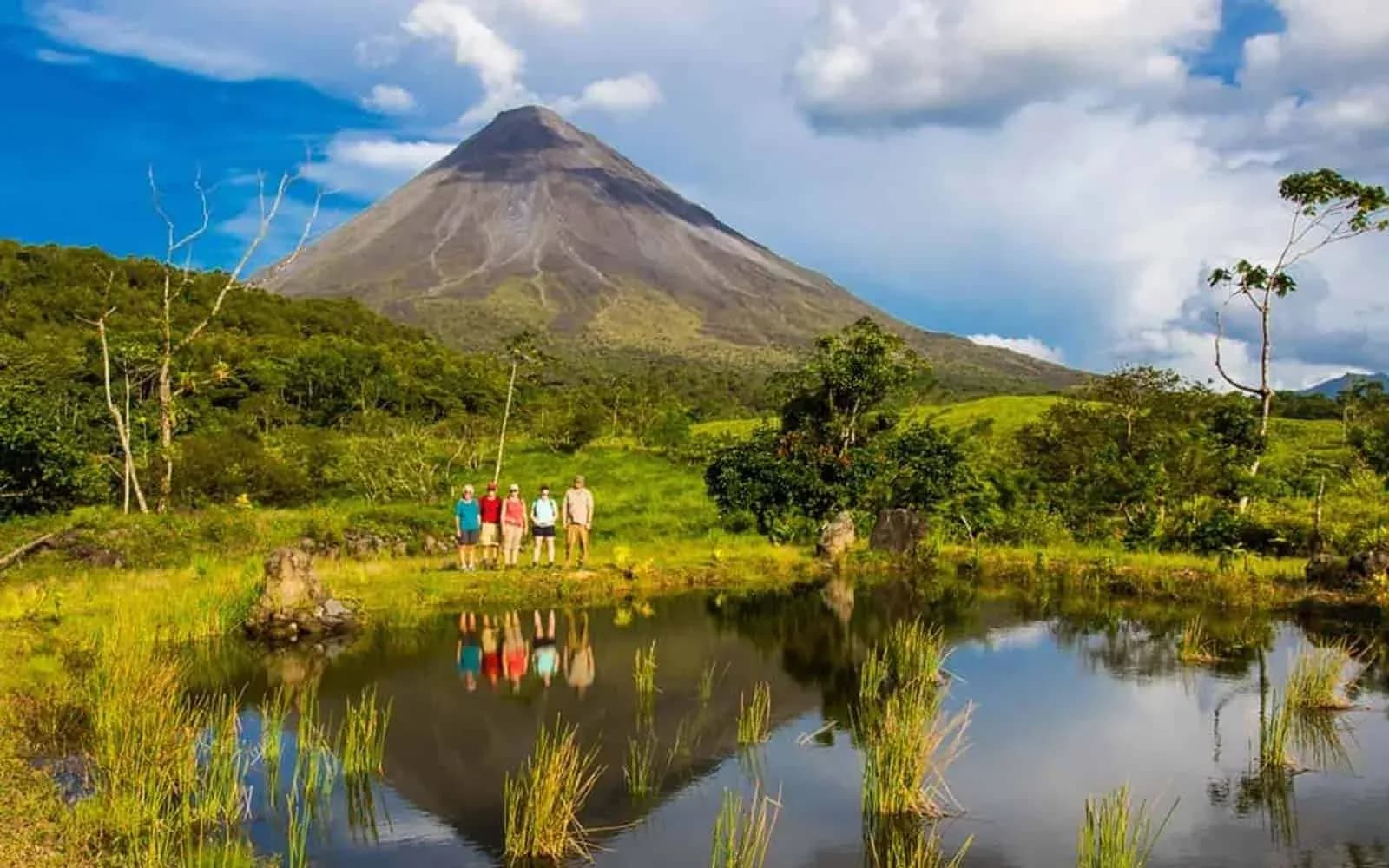 Arenal Volcano reflected in a lake with travellers on the shore, Costa Rica