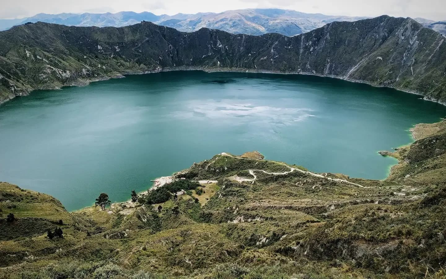 The turquoise Quilotoa crater lake ringed by the green walls of its volcanic caldera in the Ecuadorian Andes