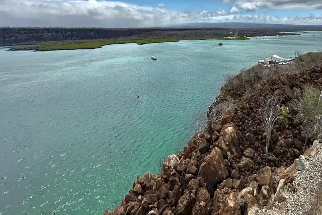 Turquoise channel and lava shoreline with a small boat at anchor, Santa Cruz island, Galápagos