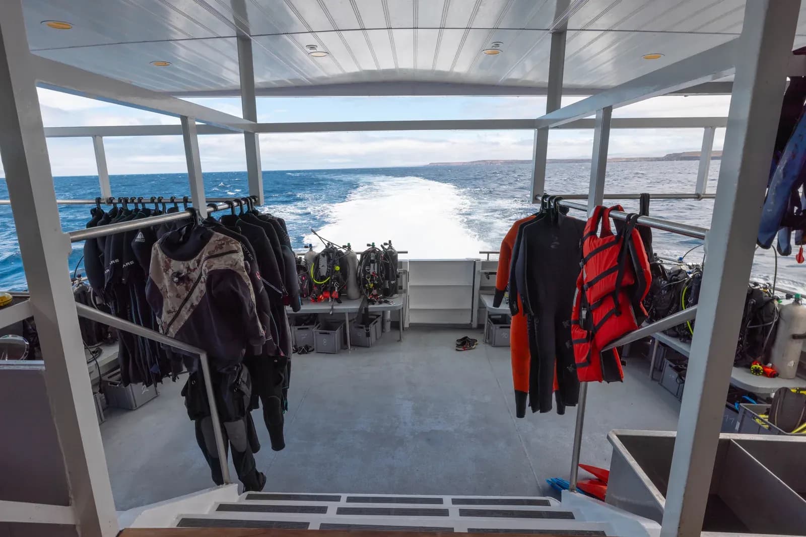 Aft dive deck with wetsuits hanging on both sides aboard Galaxy Diver II, Galápagos