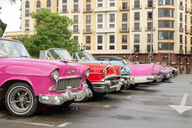 Colourful vintage American cars parked outside the Iberostar Grand Packard hotel in Havana, Cuba