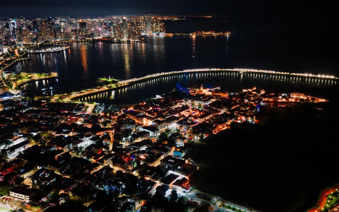 Casco Viejo old town glowing at night with the modern Panama City skyline across the bay