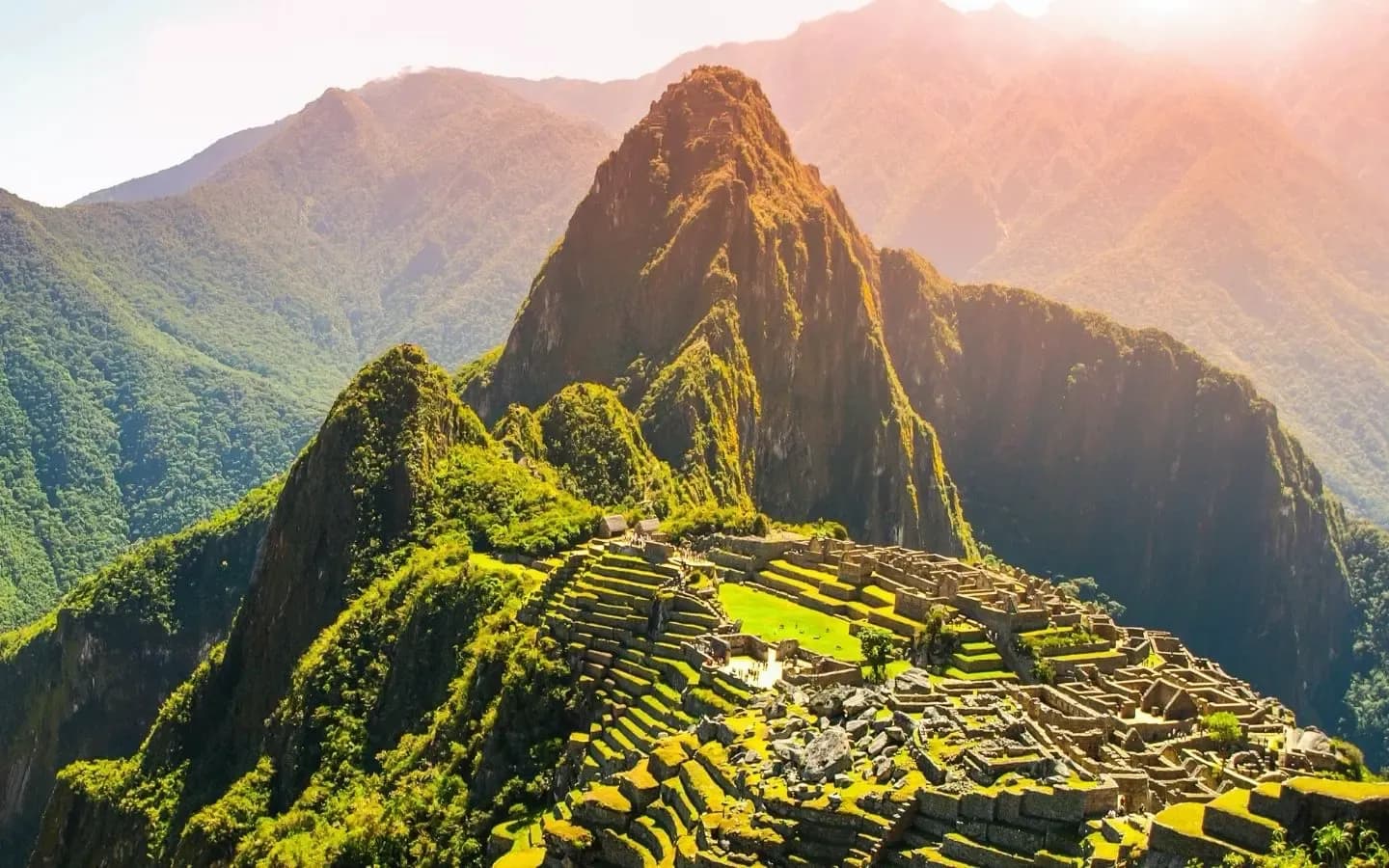 Ancient Inca ruins of Machu Picchu nestled on a mountain ridge, bathed in warm sunlight.
