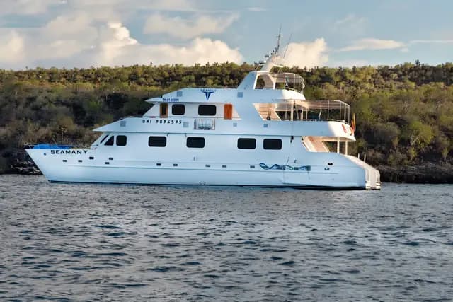 Seaman Journey catamaran anchored off a volcanic coastline, Galápagos