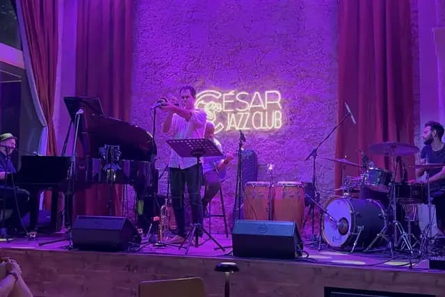 A jazz band performs on a stage under purple lights at Cesar Jazz Club.