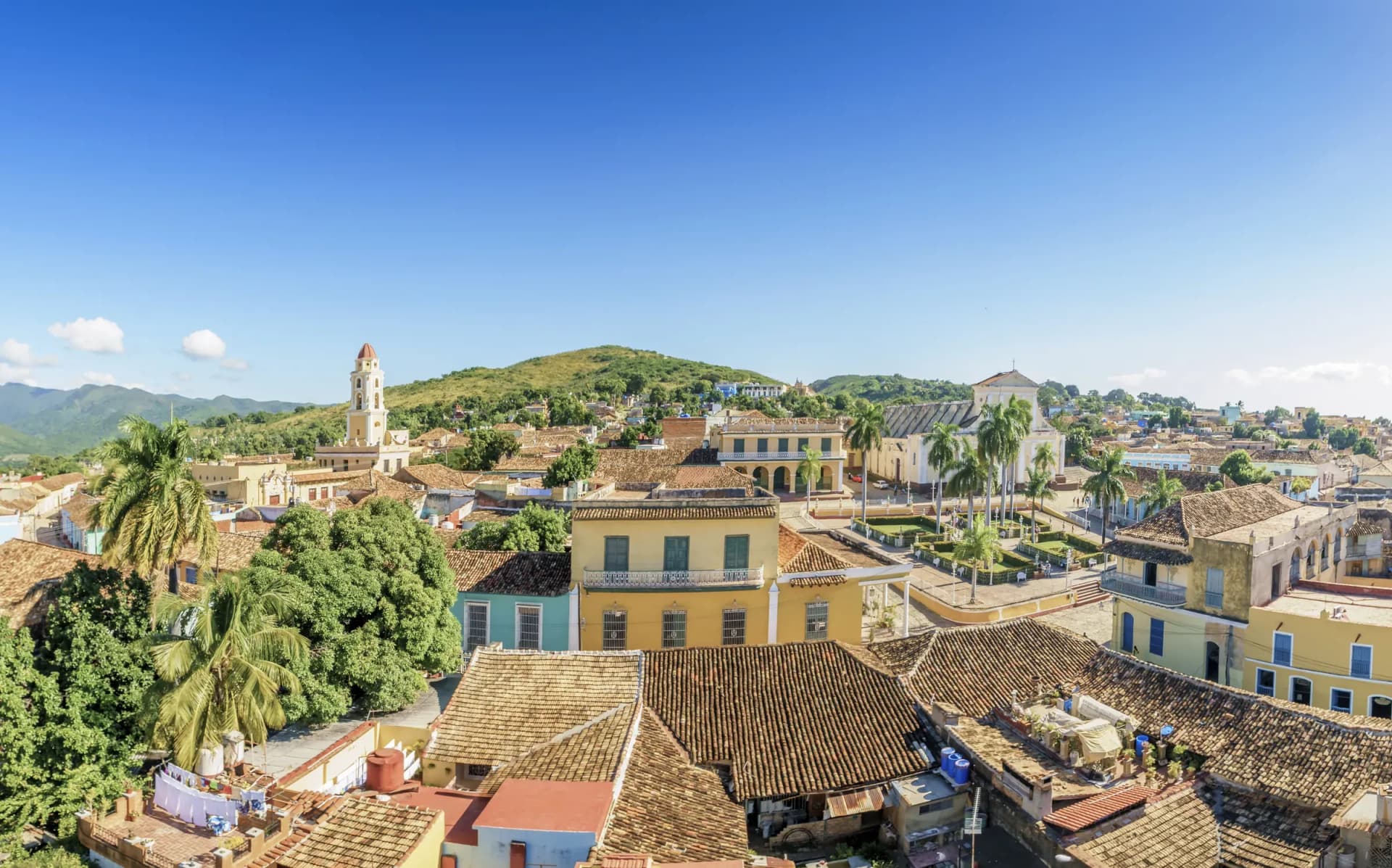 Rooftop view across Trinidad in Cuba showing terracotta tiles, colonial bell tower and the Sierra del Escambray mountains