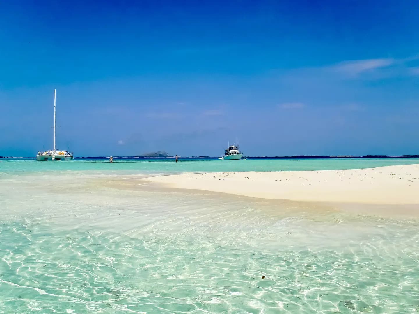 Boats anchored off a white sandbar in the turquoise water of the Los Roques archipelago, Venezuela